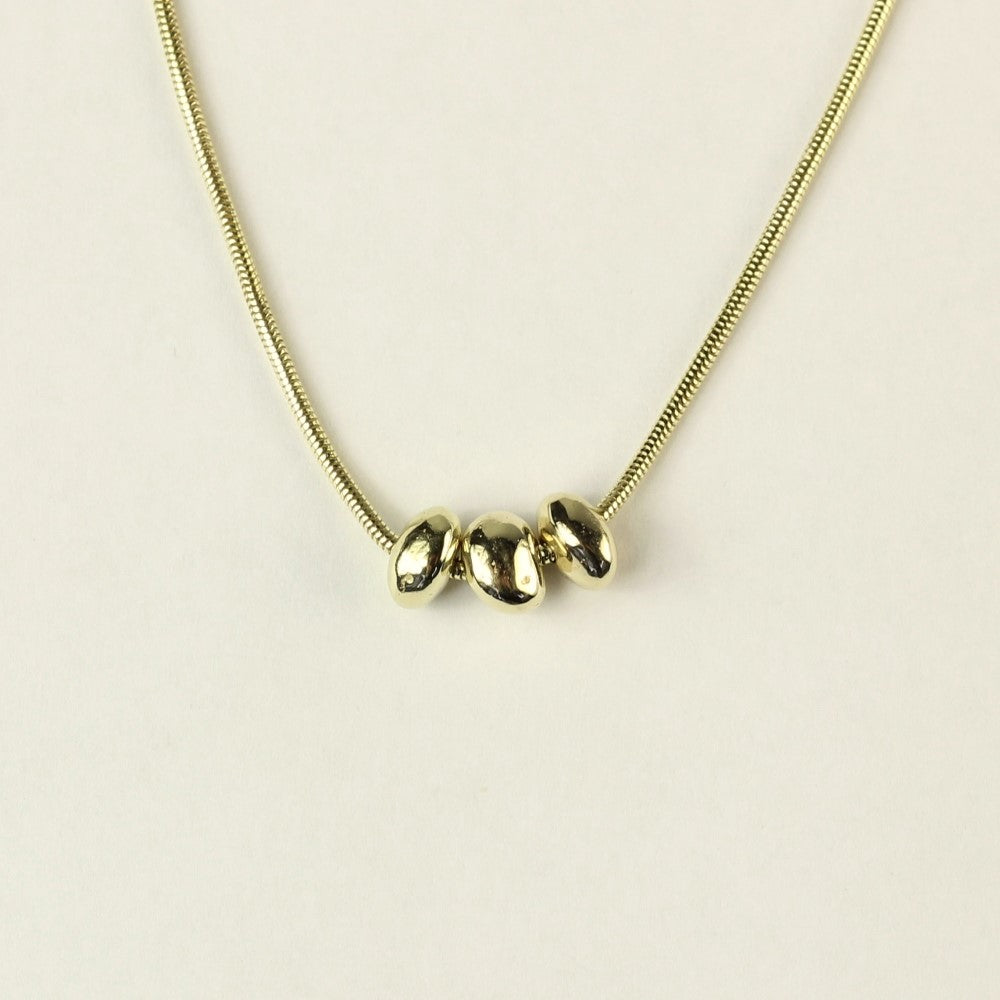 14 karaat gouden hanger Essentials: 3 minimalistische organische gouden steentjes aan een ketting. Hangend voor een witte achtergrond.