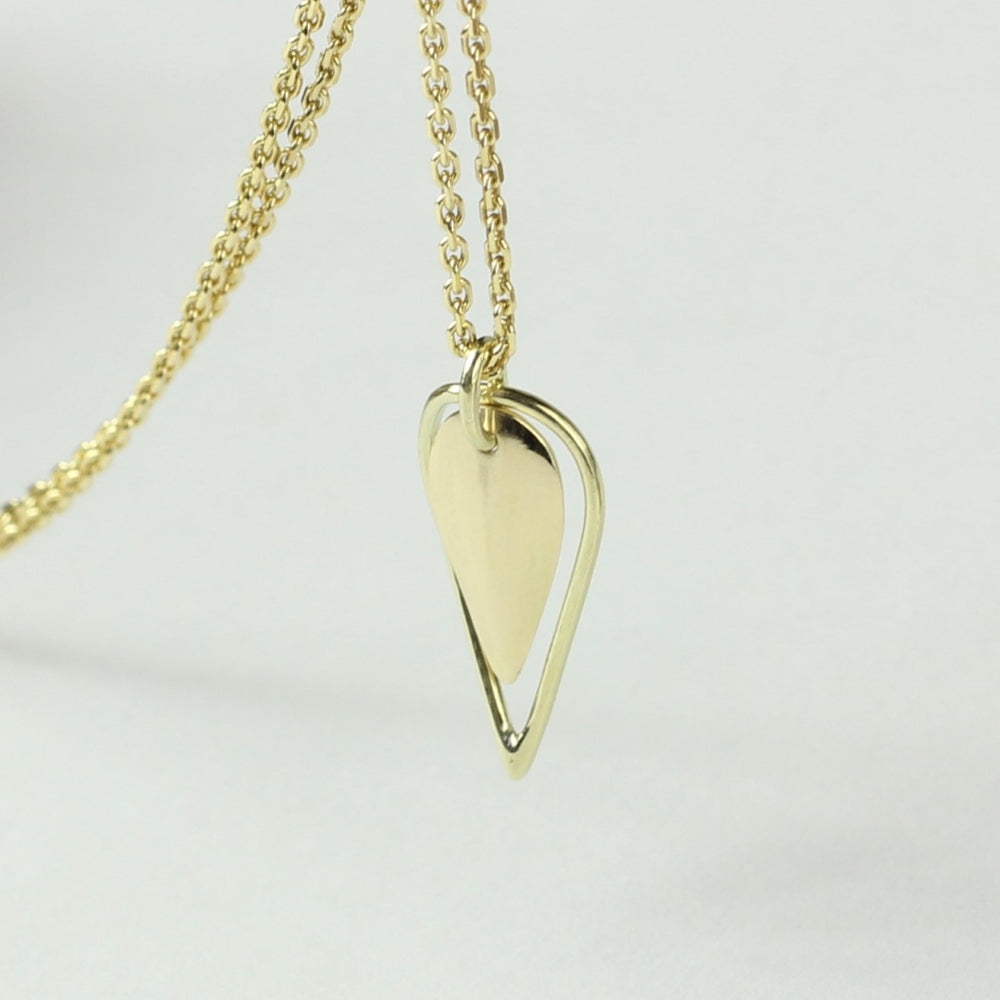 Achteraanzicht dubbel hangertje Leaves, minimalistisch gouden blaadje met daaromheen een open blaadje gemaakt van gouddraad als omlijsting. Getoont op witte achtergrond hangend aan een gouden ketting.