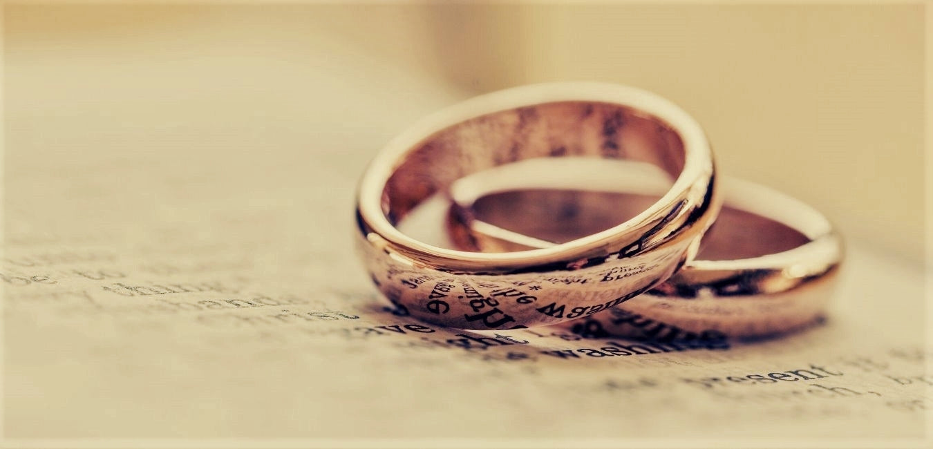 Foto van 2 gouden ringen, met het spiegelbeeld van de tekst van het boek eronder. Header foto voor homepage Monique Zonneveld Edelsmid ter illustratie van de slogan "Het sieraad dat jouw verhaal draagt".