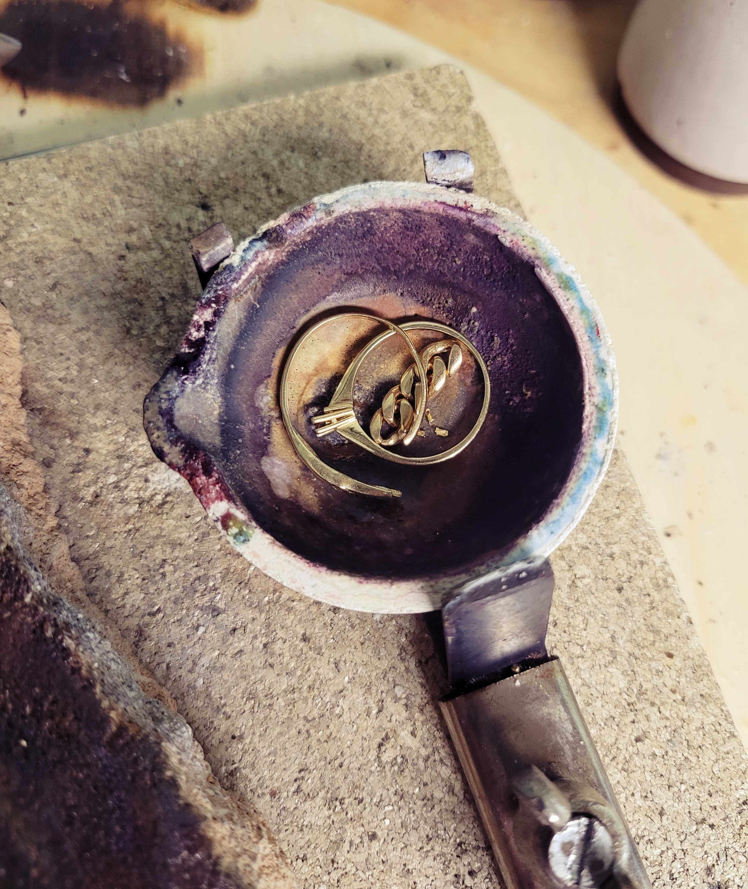 Oude gouden sieraden liggen in smeltbakje, klaar om omgesmolten te worden tot nieuw sieraad.